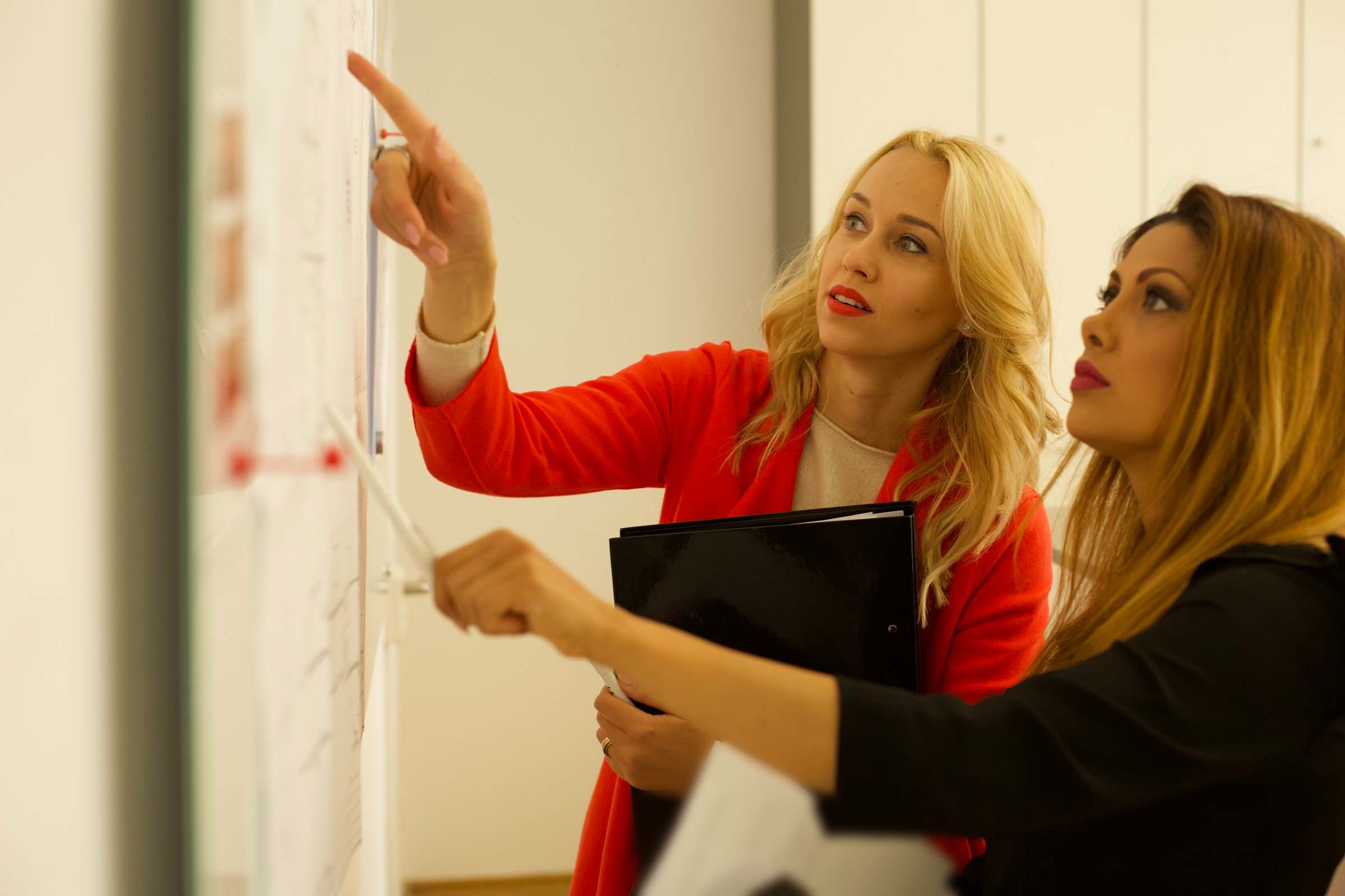 Zwei Mitarbeiterinnen der ST 77 besprechen Pläne an der Planwand